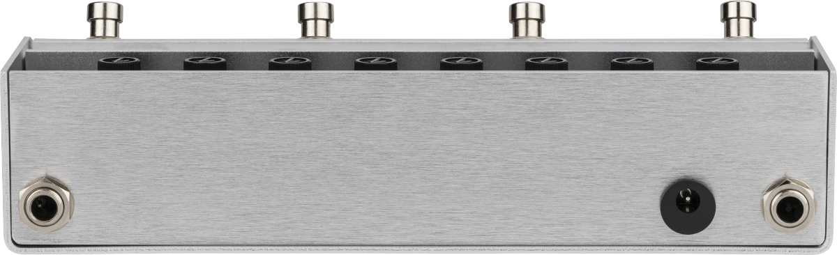 The image shows a guitar effects pedal or audio switcher with a sleek brushed metal enclosure. The top panel has 8 circular openings, likely LED indicators or switches, and 4 metal knobs or posts. The front panel features two 1/4" audio jacks and a central power or control input. This premium device is likely a loop switcher, A/B switch, or multi-channel selector for managing guitar effects or signal paths.