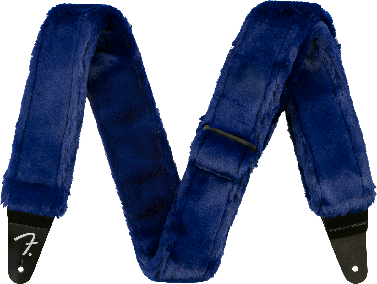 The image shows a guitar strap covered in luxurious blue fur or faux fur with black leather ends, one displaying the Fender logo. This plush, furry strap combines comfort and style, offering extra padding for long playing sessions while making a bold, eye-catching statement with its deep blue color and soft texture.