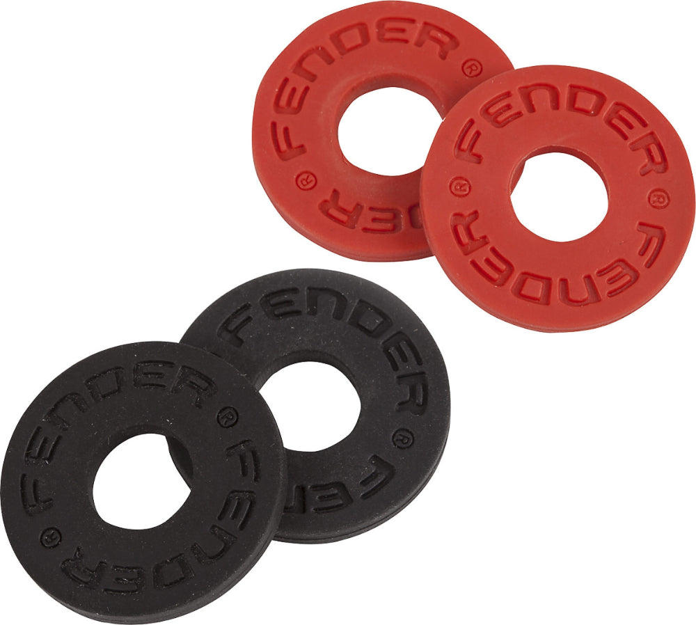 The image shows four circular rubber rings used as Fender guitar strap locks or washers. There are two red rings at the top and two black rings at the bottom. Each ring has "FENDER" and copyright symbols embossed around the edge. These accessories secure guitar straps to the instrument, preventing them from slipping off the strap pins for safer performance and practice.