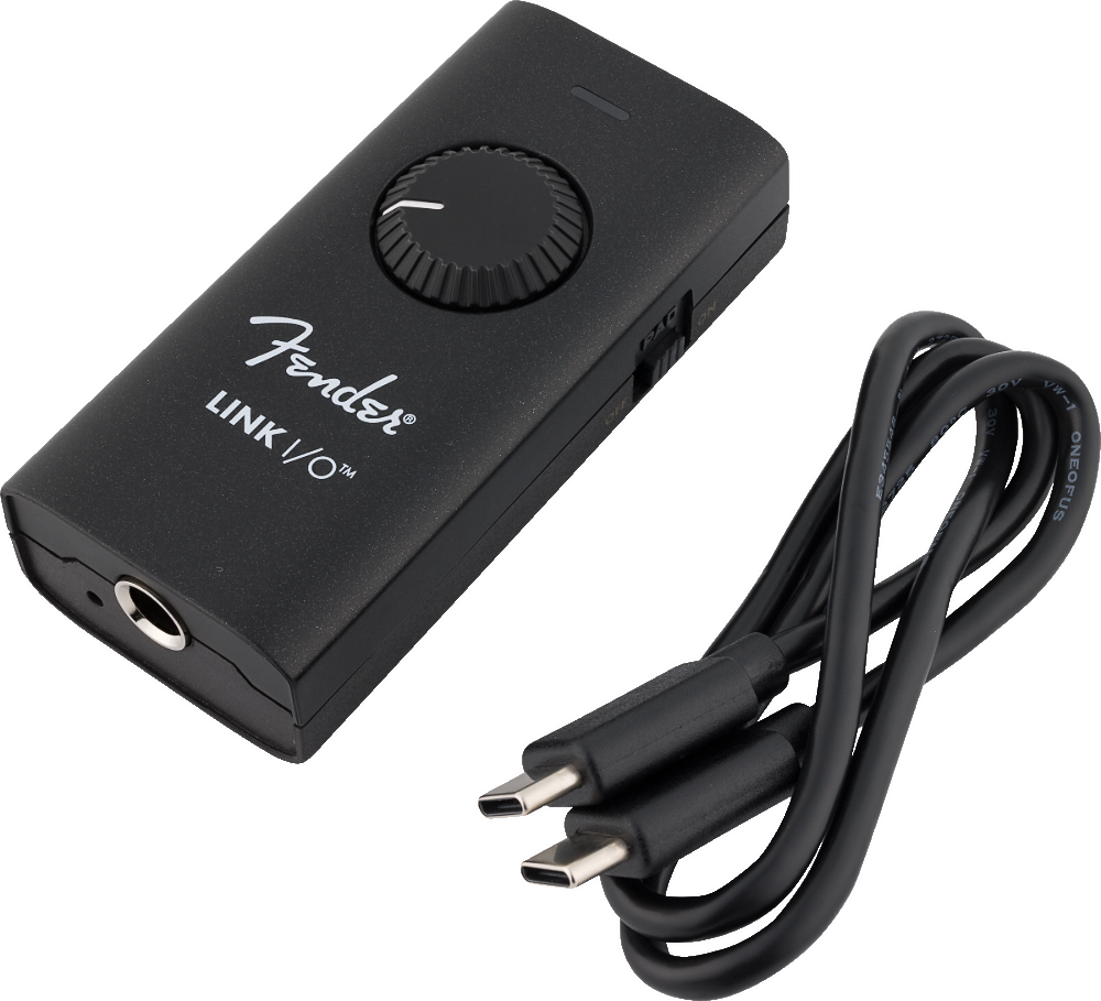 The image shows a matte black Fender Link I/O audio interface, a compact digital device for music recording. It features a large volume knob, a 3.5mm headphone jack, and a USB-C connection for computers or mobile devices. Designed for portability, it enables musicians to record instruments, monitor audio with low latency, and convert analog signals to digital, ideal for guitarists and home studios.