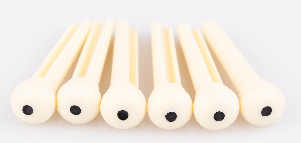 The image shows six light-colored wooden reeds, likely for woodwind instruments like clarinets or oboes, arranged in a row against a white background. Each reed is flat, thin, and rounded at one end, featuring small dark holes. The natural wood grain is visible. These reeds are essential, consumable parts for woodwind players, regularly replaced to maintain sound quality and playability.