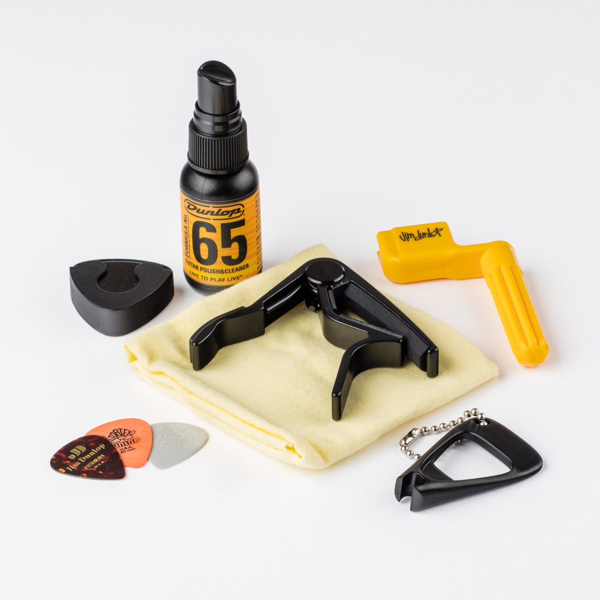 Guitar care products including a spray bottle, capo, pick, and cloth on a white background