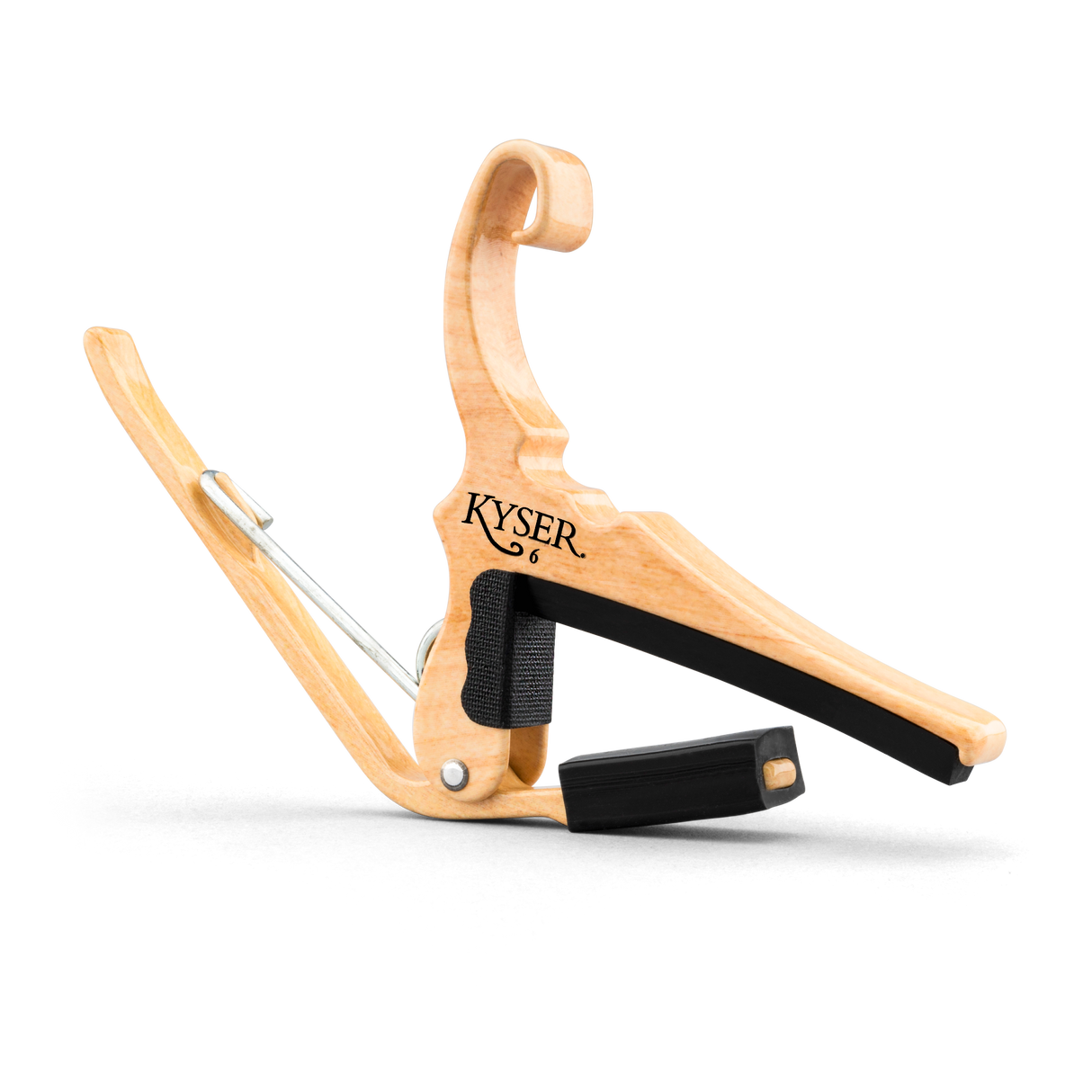 The image shows a Kyser guitar capo with a natural wooden finish. It features a spring-loaded, curved handle for one-handed use and black rubber padding to protect the fretboard and strings. The "KYSER" logo is visible, highlighting its brand. This ergonomic capo raises the pitch of all strings simultaneously, allowing guitarists to change keys easily while playing.