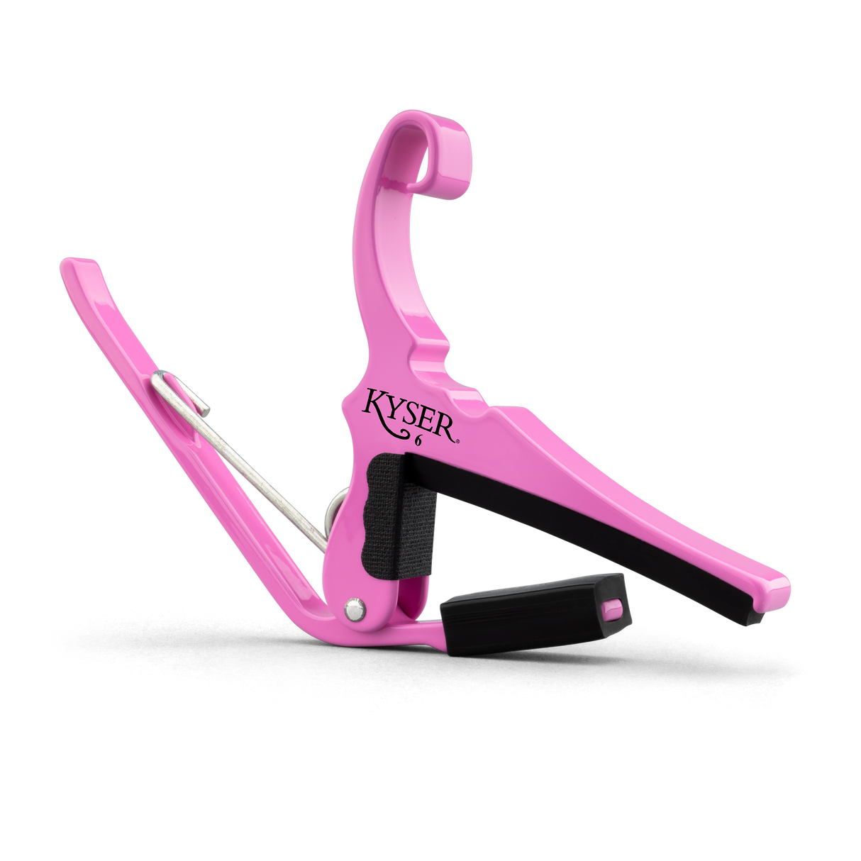 The image shows a bright pink Kyser guitar capo, a popular accessory that clamps across the fretboard to raise pitch and change keys easily. It features a spring-loaded mechanism for one-handed use, padded black contact surfaces to protect the guitar, and a curved design to fit the neck. Known for quick changes, Kyser capos are favored by guitarists seeking durability and convenience with a touch of personality.