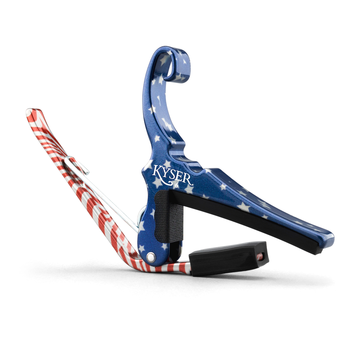 The image shows a Kyser spring-loaded guitar capo with a patriotic American flag design, featuring blue with white stars and red and white stripes. This essential accessory clamps the fretboard to raise string pitch, allowing easy key changes. Kyser capos are popular among guitarists for their functionality and quick one-handed use, combining practicality with a distinctive, decorative look.