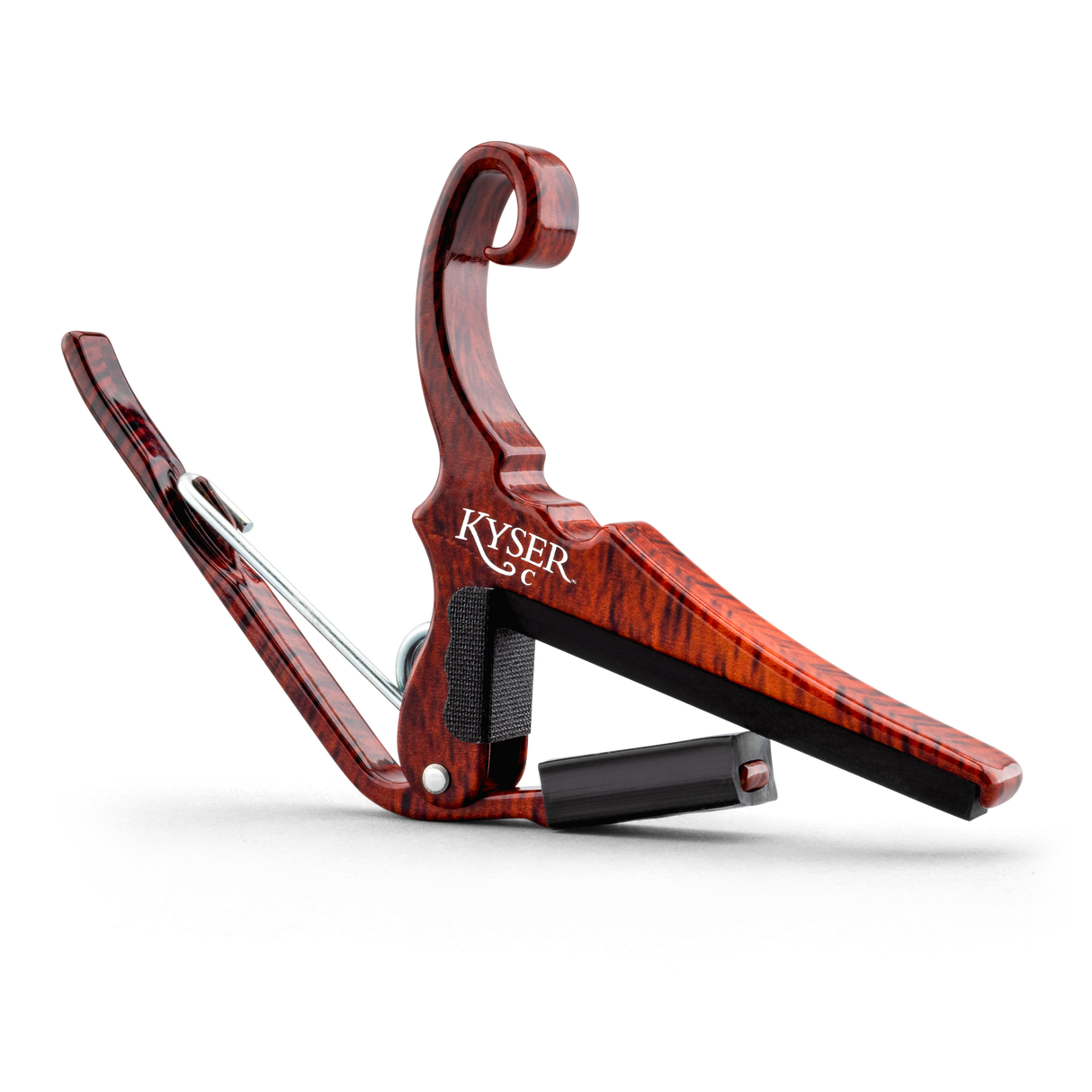 The image shows a KYSER spring-loaded guitar capo with a reddish-brown wood grain finish. It features a curved clamp arm, a padded black bar to protect strings, and a quick-release handle for easy one-handed use. Designed to clamp the fretboard and raise string pitch, this elegant capo is a practical and stylish accessory that helps guitarists change keys and achieve different chord voicings effortlessly.