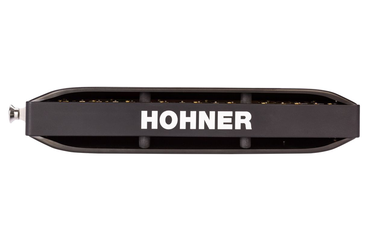 The image shows a Hohner harmonica, a well-known brand in the harmonica industry. It features a classic 10-hole diatonic design with a black comb and brass reed plates visible on top and bottom. The brand name "HOHNER" is prominently displayed in white on the body. Hohner, a German company since 1857, produces harmonicas used in many musical genres like blues, folk, and rock.
