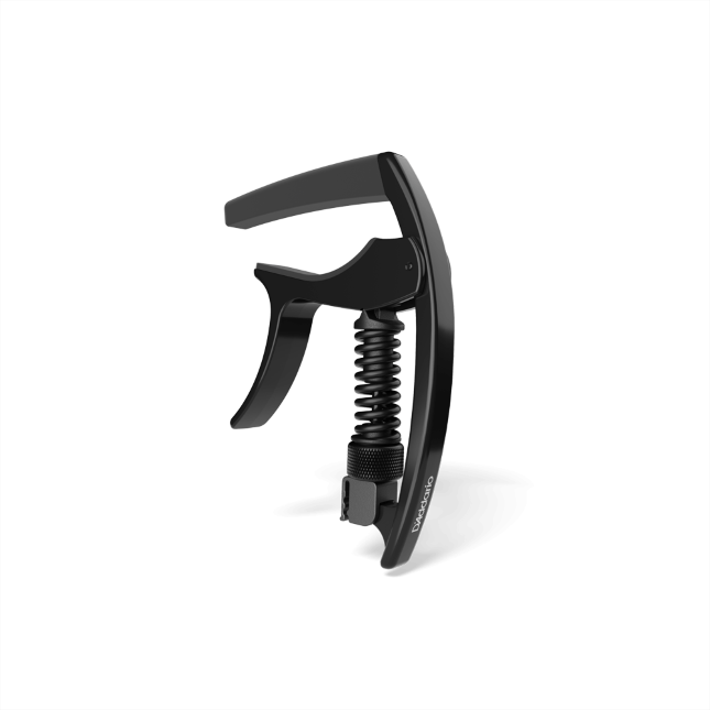 The image shows a black, spring-loaded clamp-style guitar capo with a curved mechanism, padded bar, and ergonomic handle for one-handed use. Made from metal and rubber or silicone, it features a sleek, modern design. This accessory clamps across the fretboard to raise string pitch, allowing guitarists to change keys easily while maintaining chord shapes. It appears to be a high-quality, professional-grade model.