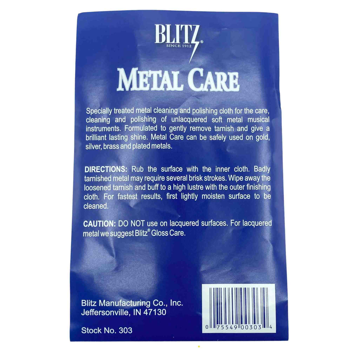 The image shows a Blitz Metal Care cloth (Stock No. 303) by Blitz, a brand established in 1912. This specialized two-part cloth is designed for cleaning and polishing unlacquered soft metal brass instruments like trumpets and trombones. Safe for gold, silver, brass, and plated metals, it removes tarnish and restores shine. The packaging warns against use on lacquered surfaces, recommending Blitz Gloss Care instead.