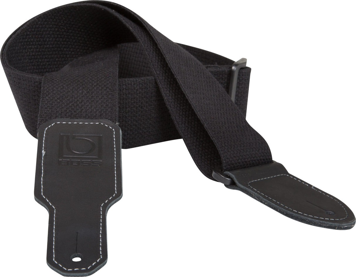 The image shows a black guitar strap made of durable fabric with a wide, padded shoulder section for comfort. It features adjustable metal buckles, leather or synthetic leather end tabs with white contrast stitching, and a visible BOSS logo on one end. Designed to support the instrument while standing, this versatile strap combines functionality and style, suitable for various guitar styles and performance settings.