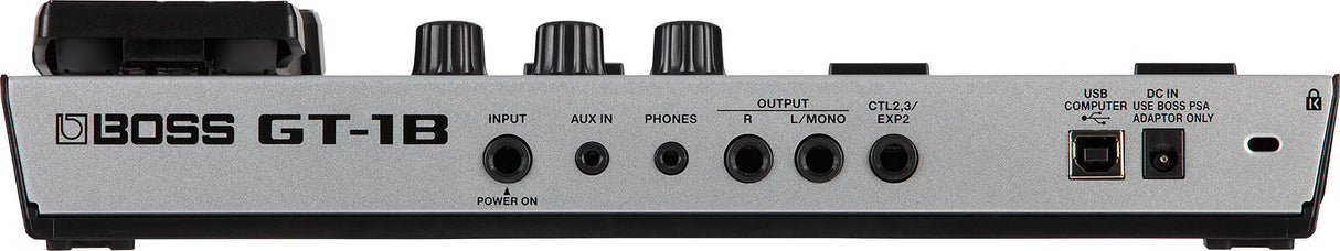 The image shows the rear panel of a Boss GT-1B bass guitar multi-effects processor pedal. It includes INPUT and AUX IN jacks, a PHONES jack, R and L/MONO OUTPUTs, CTL2,3/EXP2 control jacks, a USB port, DC IN power jack, and a power switch. This compact digital unit offers various effects and USB connectivity for recording and editing, made by the well-known Boss brand.