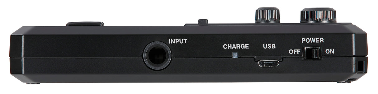 The image shows a black electronic music device, likely a guitar effects pedal or multi-effects processor. It features an INPUT jack on the left, a USB port, a CHARGE indicator, a POWER switch on the right, two control knobs on top, and a footswitch button. It is rechargeable and designed for musicians to add sound effects, with USB connectivity for updates or recording.