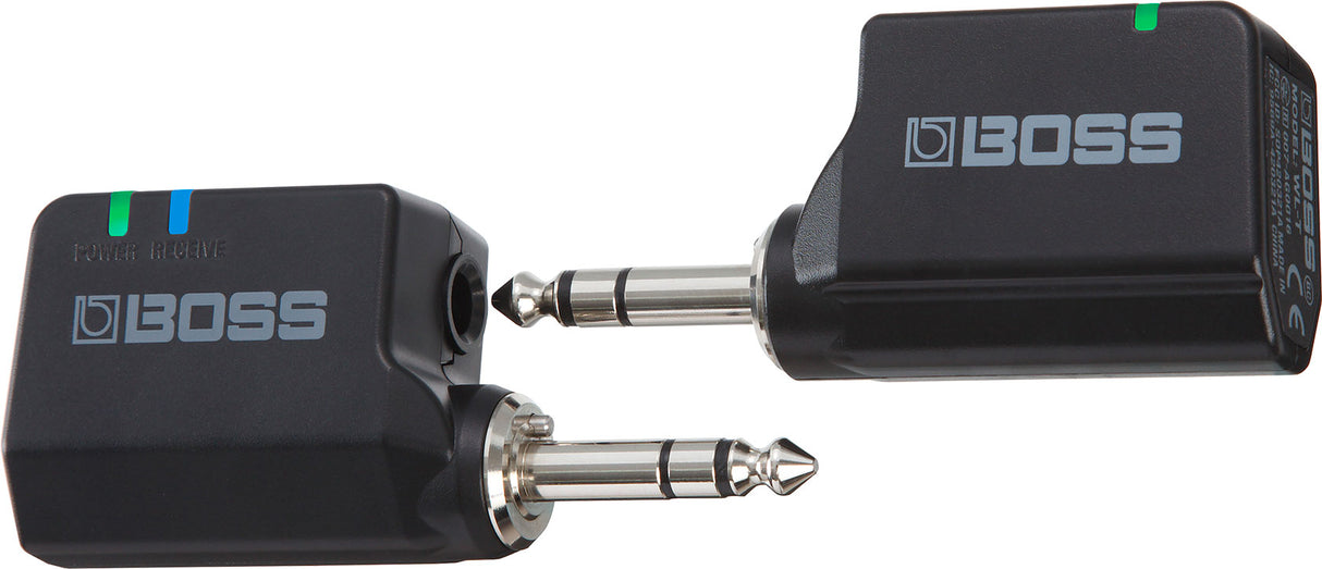 The image shows a BOSS wireless guitar system with two black units: a transmitter (left) that plugs into the guitar’s 1/4" output jack, and a receiver (right) that connects to an amplifier or pedalboard. Both feature BOSS branding and indicator lights, signaling power and connection. This system allows musicians to play wirelessly, offering freedom of movement without cables while maintaining reliable audio quality.