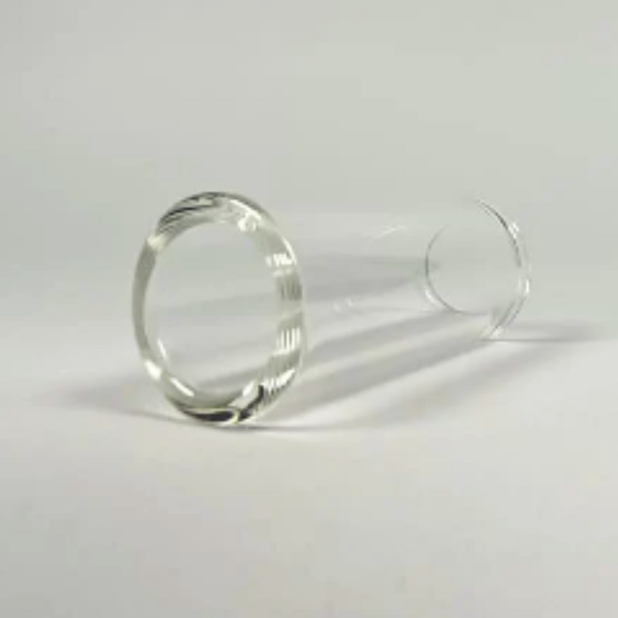The image shows a clear glass guitar slide, also known as a bottleneck slide, designed to fit over a finger. It’s used in slide guitar playing to produce smooth, clear tones and the distinctive sliding sound heard in blues, country, and rock. Glass slides offer a warmer, mellower tone compared to metal and enable expressive glissando effects. This medium-wall slide is typically worn on the ring or pinky finger.