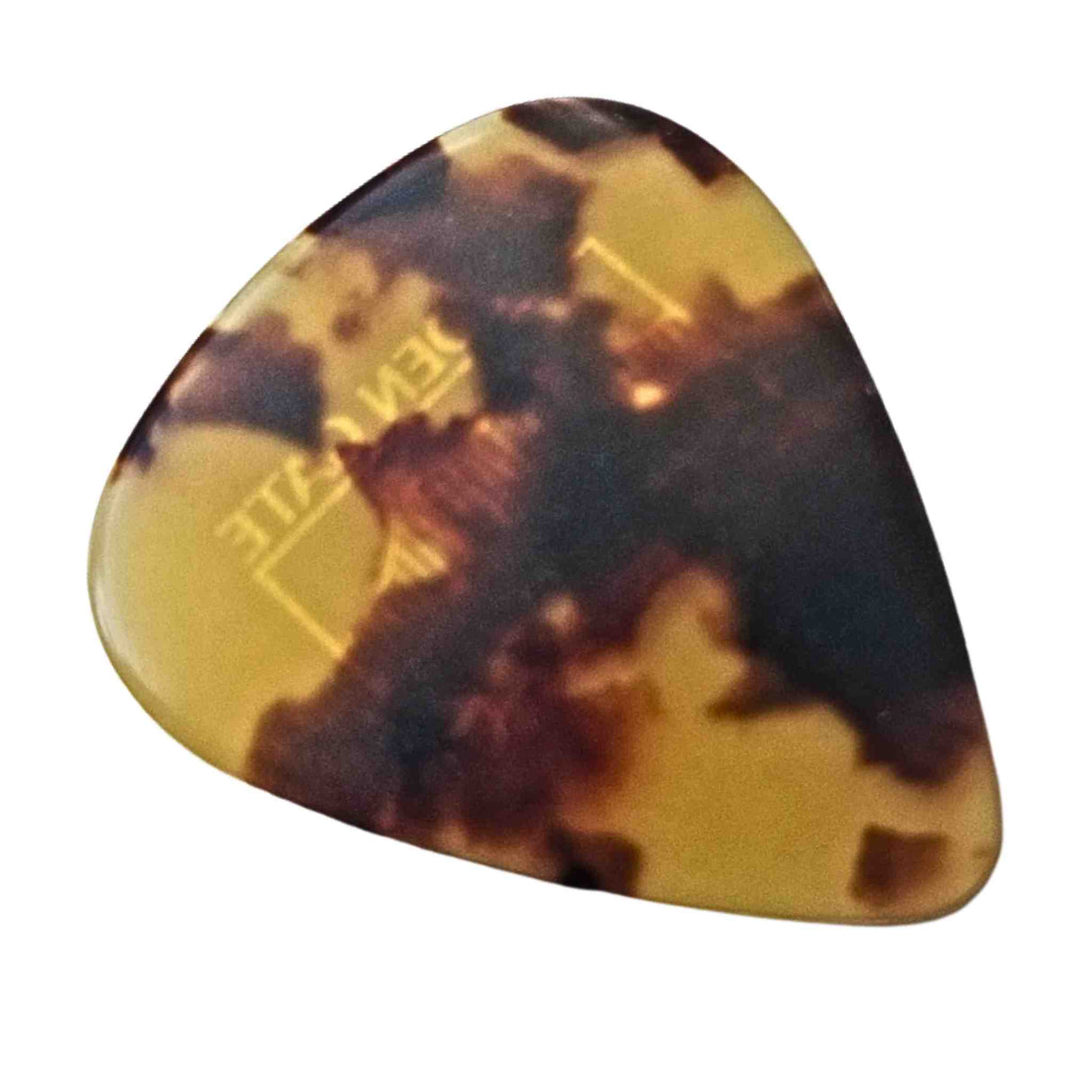 The image shows a teardrop-shaped guitar pick with a classic tortoiseshell pattern in mottled brown, amber, and dark brown hues. Made from celluloid or similar plastic, it mimics traditional tortoiseshell material, which is now protected. Some embossed text is visible but unclear. This pick style is favored by musicians for its vintage look and tonal qualities, used to strum or pluck guitar strings.