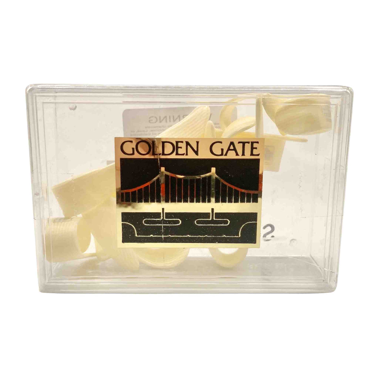 The image shows a clear plastic case labeled "GOLDEN GATE" with a logo of the Golden Gate Bridge, containing several light-colored cane reeds. These flat, thin, slightly curved single reeds are used for woodwind instruments like saxophones or clarinets. The transparent case protects the reeds from damage and moisture while allowing musicians to view them.