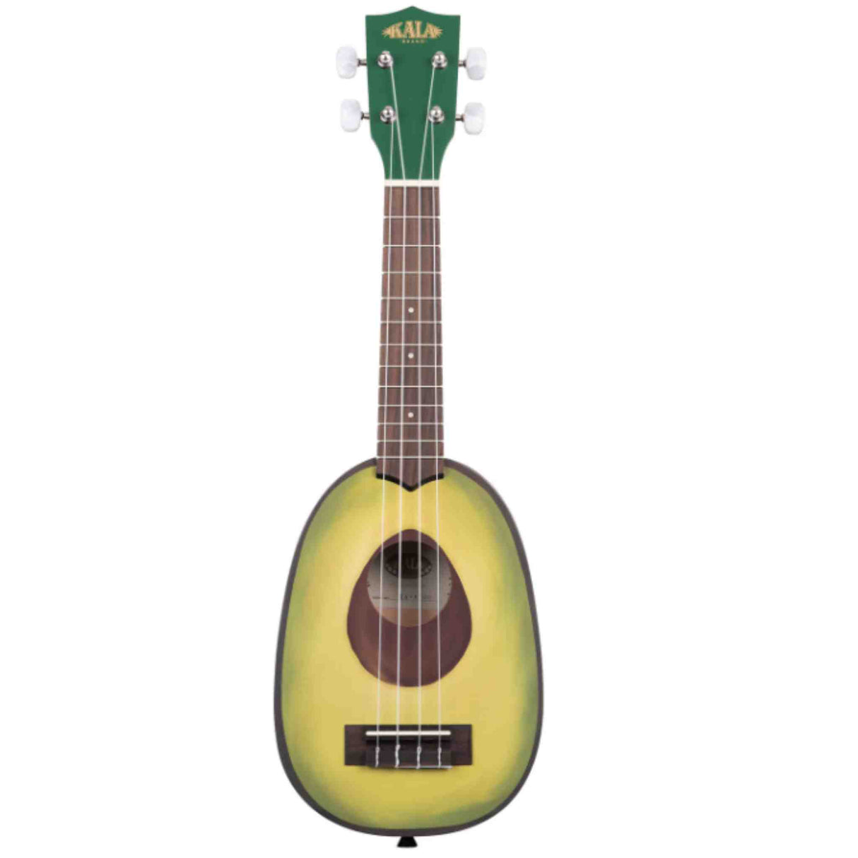 The image shows a novelty soprano ukulele by Kala designed to look like an avocado. It features a green and yellow-green body shaped like an avocado with a brown center representing the pit as the sound hole. The ukulele has a brown wooden neck with frets, four strings, white tuning pegs, and a green headstock with the Kala logo. This playful, food-inspired design combines fun aesthetics with full musical functionality.