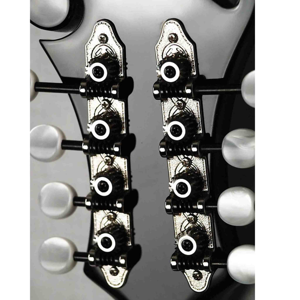 The image shows two parallel rows of tuning pegs on a light-colored wooden guitar headstock. Each peg has a white or cream-colored button attached to black tuning machines mounted on chrome plates. These sealed gear tuning machines, common on acoustic and electric guitars, are essential for adjusting string tension and tuning. The hardware appears clean, professional, and in good condition.