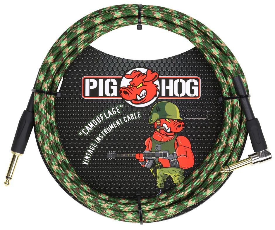 The image shows a Pig Hog "Camouflage" vintage guitar cable with a green, brown, and tan woven fabric jacket. It features the Pig Hog red pig logo and a military-themed cartoon pig in combat gear holding a guitar. The cable has professional 1/4" gold-plated connectors, with one straight and one right-angle plug, designed for electric guitars and basses.