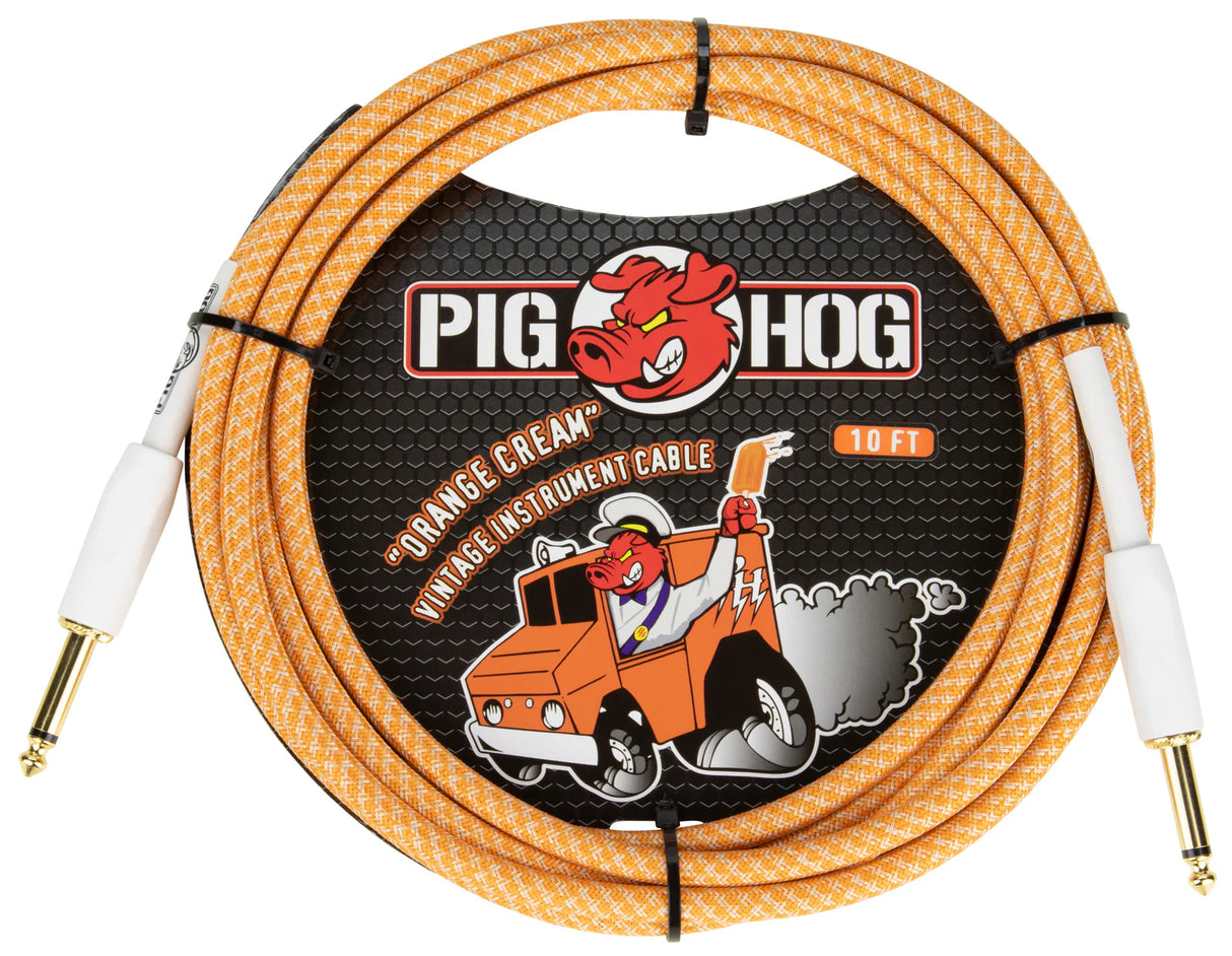 The image shows a Pig Hog "Orange Cream" vintage-style 10-foot instrument cable with an orange and white braided jacket, gold-plated 1/4" TS connectors, and white connector boots. The packaging features the Pig Hog logo with a red pig mascot and a cartoon pig driving an orange delivery truck. This cable is designed for electric guitars, basses, and other instruments, combining retro looks with reliable, professional performance.