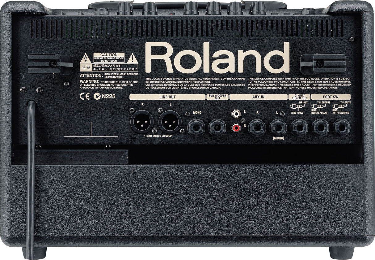 The image shows the back panel of a Roland guitar amplifier featuring a prominent logo, multiple input/output connections including LINE OUT (XLR), SUB WOOFER, AUX IN, 1/4" jacks, and footswitch ports. It has control knobs along the top, safety and certification labels, ventilation grilles, and a black textured finish. This modern amp offers extensive connectivity for live or studio use.