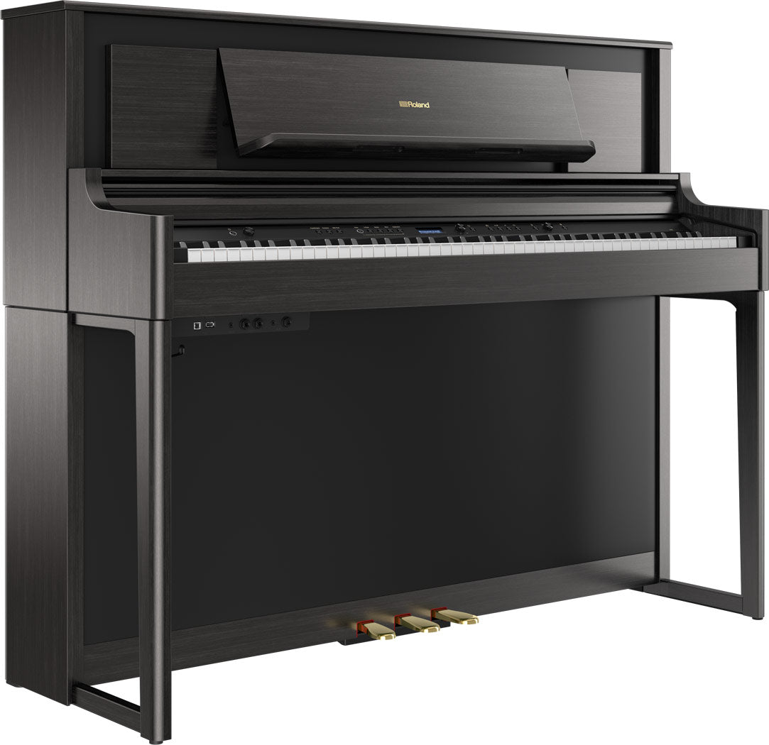 The image shows a Roland upright-style digital piano with a sleek dark wood finish. It features a full 88-key keyboard, three pedals, a digital control panel with buttons and a small display, a music rack, and the Roland logo on the top panel. Its modern, furniture-like design offers a space-efficient alternative to a grand piano while delivering an authentic piano playing experience with digital capabilities.