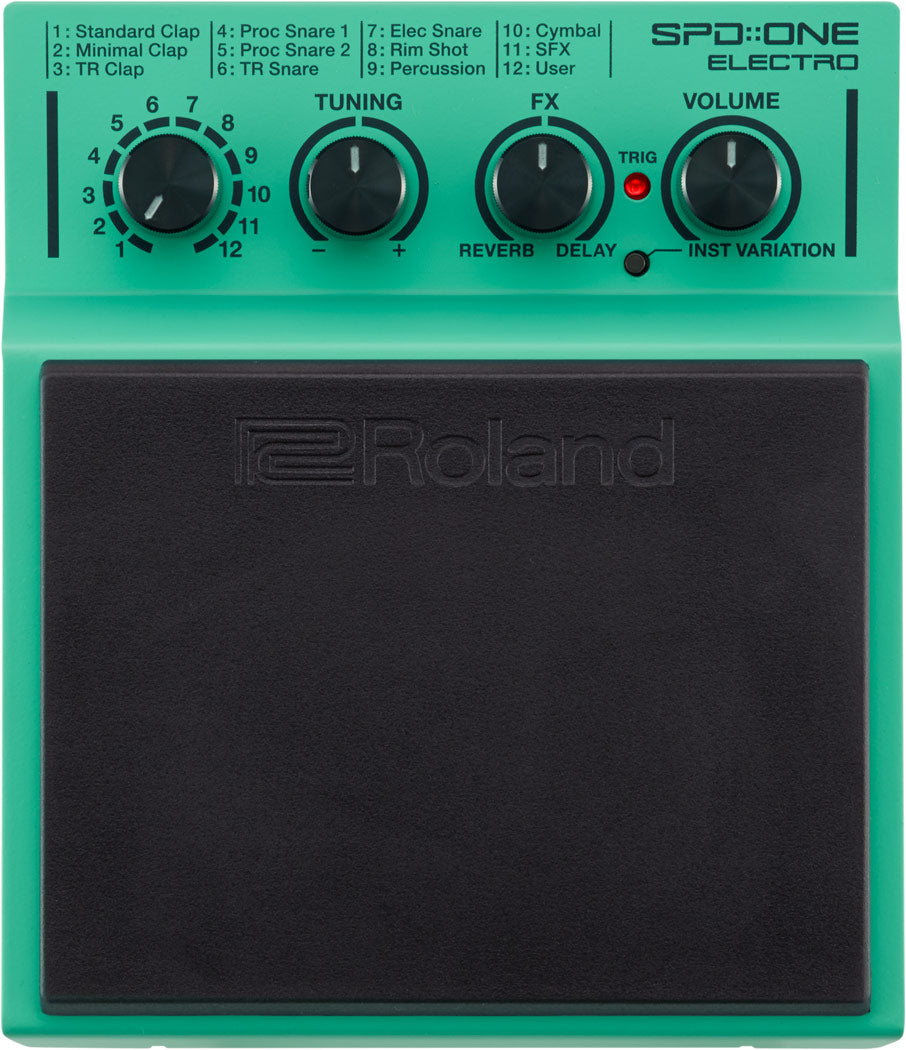 The image shows a Roland SPD::ONE ELECTRO electronic percussion pad with a green/teal housing and large black rubber playing surface. It features a 12-position selector knob for sound presets, three control knobs for TUNING, FX, and VOLUME, plus red TRIG and INST VARIATION buttons. Compact and portable, it’s designed for drummers to trigger electronic sounds via sticks or hands.