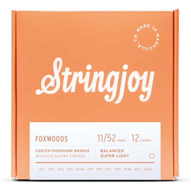 The image shows a package of Stringjoy Foxwoods coated phosphor bronze acoustic guitar strings for 12-string guitars. The balanced super light set is gauge 11/52. The orange/coral box features the Stringjoy logo, technical specs on a white label, a "Made in Nashville" badge, and lists individual string gauges. The packaging suggests a premium, corrosion-resistant string set.