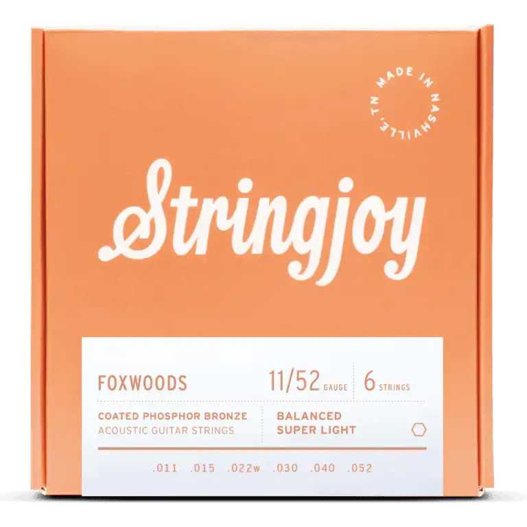 The image shows a package of Stringjoy Foxwoods coated phosphor bronze acoustic guitar strings. The orange/coral box features a script-style logo, a "Made in Nashville" badge, and a white label listing specs. This 6-string set is Balanced Super Light gauge 11-52 (.011, .015, .022w, .030, .040, .052), offering warm tone and corrosion resistance.