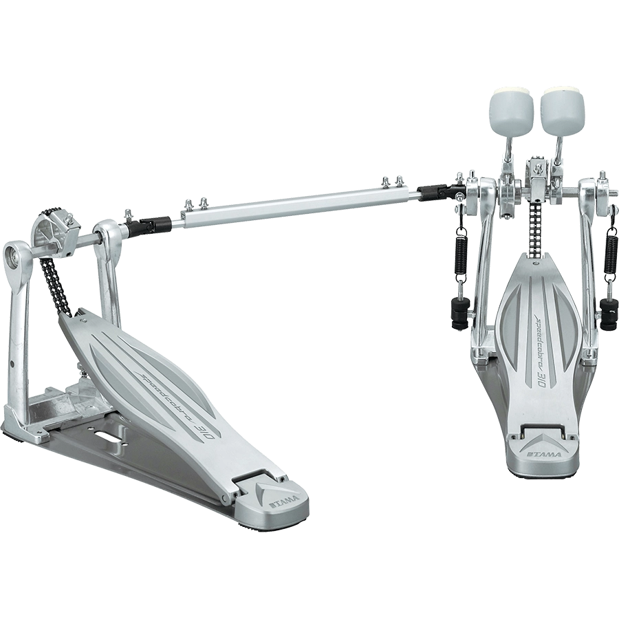 The image shows a high-end double bass drum pedal with dual foot pedals connected by a drive shaft, featuring chain or belt drive, adjustable white/felt beaters, sturdy metal frame, spring returns, and customizable tension and positioning. Made by Tama, this professional-grade pedal enables drummers to play fast, complex bass drum patterns used in metal, rock, and jazz.