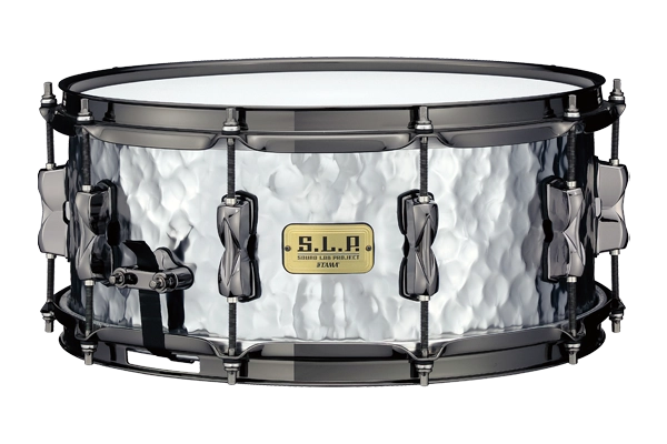 The image shows a TAMA S.L.P. snare drum with a distinctive hammered metal shell and black hardware. It features tension rods around the circumference, a snare throw-off lever, and the TAMA S.L.P. badge. This professional-quality drum, likely made of steel or aluminum, combines a textured finish that enhances both its look and sound, suitable for various musical styles.