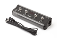 The image shows a Fender guitar amplifier footswitch with a black metal body, four metal-capped footswitches, and the Fender logo. It includes a long cable for connecting to an amp. Designed for stage use, this compact device lets guitarists remotely switch amp channels and toggle effects hands-free during performances.