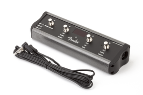 The image shows a Fender guitar amplifier footswitch with a black metal body, four metal-capped footswitches, and the Fender logo. It includes a long cable for connecting to an amp. Designed for stage use, this compact device lets guitarists remotely switch amp channels and toggle effects hands-free during performances.