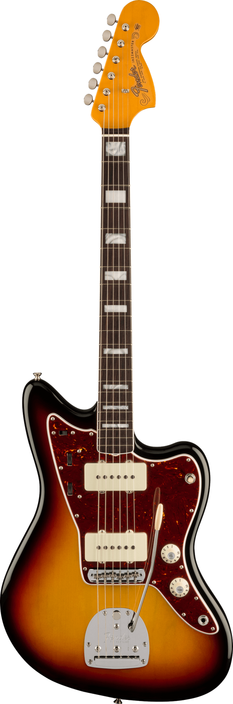 The image shows a Fender Jazzmaster electric guitar with a sunburst offset body, tortoiseshell pickguard, and two cream single-coil pickups. It features a chrome Jazzmaster tremolo, multiple control knobs, and chrome hardware. The maple headstock displays the Fender logo with six chrome tuners. The dark rosewood fretboard has white block inlays and binding. This classic American guitar is known for its unique tone and versatile use across genres.