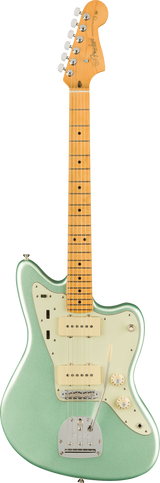 The image shows a Fender Jazzmaster electric guitar with an offset waist body in glossy surf green, a cream pickguard, and chrome hardware. It features two single-coil pickups, individual volume and tone controls, a rhythm/lead switch, a chrome tremolo tailpiece, and adjustable bridge. The maple neck has dot inlays, six chrome tuners, and a classic Fender headstock with logo. This iconic model is popular for its distinctive tone and comfortable playability.