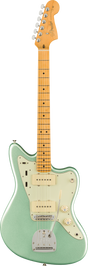 The image shows a Fender Jazzmaster electric guitar with an offset waist body in glossy surf green, a cream pickguard, and chrome hardware. It features two single-coil pickups, individual volume and tone controls, a rhythm/lead switch, a chrome tremolo tailpiece, and adjustable bridge. The maple neck has dot inlays, six chrome tuners, and a classic Fender headstock with logo. This iconic model is popular for its distinctive tone and comfortable playability.