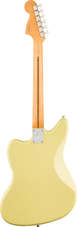 The image shows the back of a Fender-style electric guitar featuring a maple neck with a skunk stripe, a metal neck plate with the Fender logo, and a cream or vintage white offset body. The headstock has six inline tuning pegs. The design and bolt-on neck suggest it’s a classic Jazzmaster or Jaguar model, highlighting traditional Fender craftsmanship and vintage aesthetics.