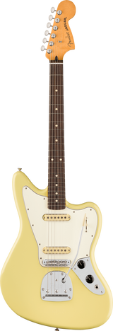 The image shows a Fender Jaguar electric guitar with its iconic offset body, cream single-coil pickups, white pickguard, multiple switches, rosewood fretboard with dot inlays, vintage-style tuning pegs, and a light yellow/cream finish. The "Jaguar" logo is visible on the headstock. Known for its 24" scale and unique tremolo, this classic model is popular among indie and surf rock musicians.