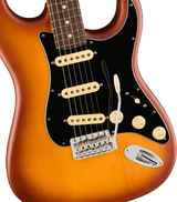 The image shows a close-up of a Stratocaster-style electric guitar with a sunburst finish, transitioning from orange edges to a cream center. It features three cream single-coil pickups, a black pickguard, chrome tremolo bridge, two cream tone knobs, a five-way selector switch, and an input jack. The maple neck has a dark rosewood fretboard with dot inlays and metal frets, showcasing a high-quality, professional-grade instrument.