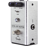 The image shows a Fender Level Set Buffer guitar effects pedal in a brushed aluminum enclosure. It features Level and Hi-Freq knobs, a Load switch, a Mute footswitch, and 1/4" input/output jacks. This pedal preserves signal integrity and tone in long cable runs or complex setups, allowing level adjustment while maintaining the guitar’s natural sound. Fender branding is visible on the pedal.