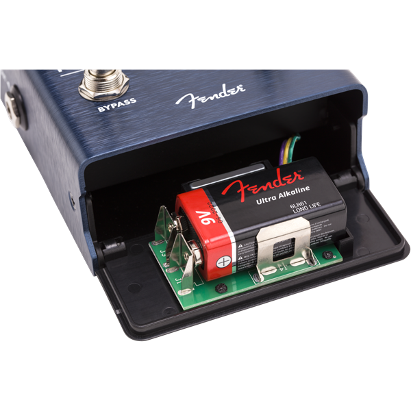 The image shows a Fender guitar effects pedal with a dark blue brushed metal finish and the Fender logo. Its battery compartment is open, revealing a green circuit board, a 9V Fender Ultra Alkaline battery with red and black labels, and connecting wires. Visible are the "BYPASS" switch and a 1/4" input jack. This typical setup illustrates the pedal’s internal electronics powering guitar effects either by battery or adapter.