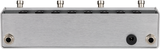 The image shows a guitar effects pedal or audio switcher with a sleek brushed metal enclosure. The top panel has 8 circular openings, likely LED indicators or switches, and 4 metal knobs or posts. The front panel features two 1/4" audio jacks and a central power or control input. This premium device is likely a loop switcher, A/B switch, or multi-channel selector for managing guitar effects or signal paths.