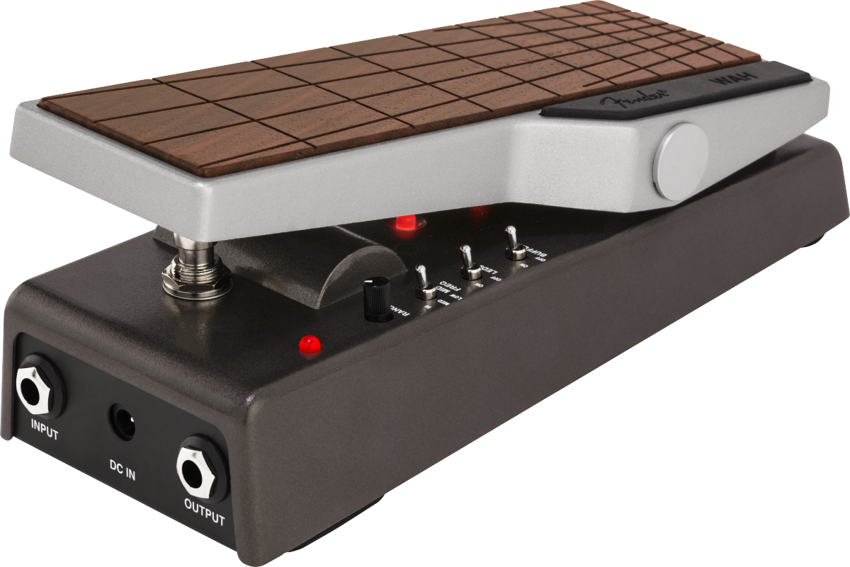 The image shows a guitar effects pedal, likely a wah pedal, with a hinged wood-grain treadle for foot control. It features toggle switches, a rotary knob, red LED indicators, 1/4" input/output jacks, and a DC power input. Housed in a durable metal enclosure, this pedal is used to create the classic "wah-wah" sound by filtering frequencies as the treadle rocks back and forth.