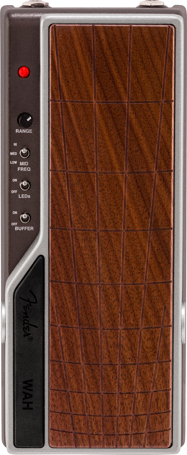The image shows a wah expression pedal for electric guitar or bass, featuring a wood-grain textured footplate, control knobs and switches on the left side labeled RANGE, frequency settings (HI, MED, LOW MID, FREQ), LED and buffer ON/OFF switches, a red indicator LED at the top, and "WAH" branding on the lower left. The pedal creates the classic "wah-wah" sound by rocking it with the foot.