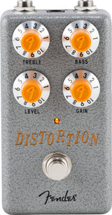 The image shows a Fender distortion pedal with a gray textured metal casing and four orange knobs labeled Treble, Bass, Level, and Gain, each numbered 0-10 and featuring the Fender "F" logo. It includes input/output jacks, a footswitch, an LED indicator, and the Fender script logo. This pedal modifies electric guitar sound by adding distortion and overdrive effects.