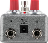 The image shows a guitar effects pedal, likely a distortion or overdrive type, with two red-topped control knobs, a central footswitch, input/output jacks labeled "IN" and "OUT," a 9V DC power input, a small red LED indicator, and a textured gray/silver metal casing. This pedal modifies electric guitar sound by adding distortion or overdrive between the guitar and amplifier.