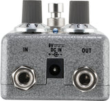 The image shows a guitar effects pedal with a textured gray/silver finish. It features two black ribbed control knobs, a metal footswitch, 1/4" input/output jacks labeled "IN" and "OUT," a 9V DC power input, and a small blue LED indicator. Designed to modify guitar sound, it connects between guitar and amplifier. Its sturdy metal build and professional components make it suitable for studio and live use.