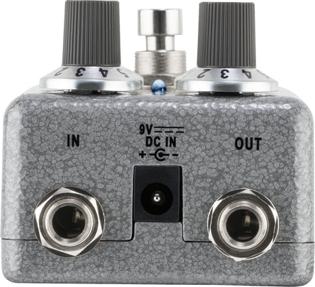 The image shows a guitar effects pedal with a textured gray/silver finish. It features two black ribbed control knobs, a metal footswitch, 1/4" input/output jacks labeled "IN" and "OUT," a 9V DC power input, and a small blue LED indicator. Designed to modify guitar sound, it connects between guitar and amplifier. Its sturdy metal build and professional components make it suitable for studio and live use.