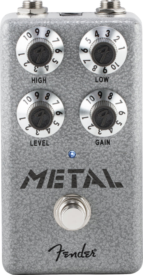 The image shows a Fender "Metal" distortion guitar effects pedal with a gray textured finish. It has four knobs—High (treble), Low (bass), Level (output volume), and Gain (distortion). The pedal includes two jacks at the top, a footswitch at the bottom, an LED indicator, and the Fender logo. Designed for heavy, distorted tones ideal for metal and hard rock guitar.