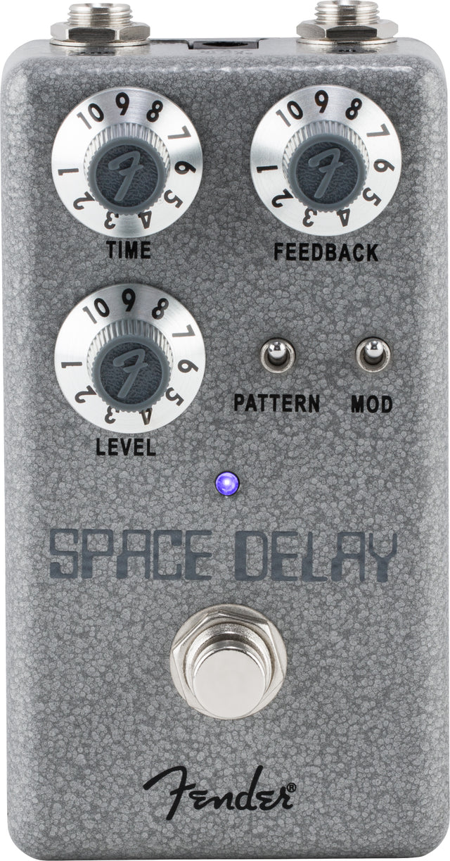 The image shows a Fender Space Delay guitar effects pedal with a compact gray/silver textured design. It has three main knobs (TIME, FEEDBACK, LEVEL), two smaller toggle switches (PATTERN, MOD), input/output jacks, a footswitch, a blue LED indicator, and the Fender logo. This digital delay pedal creates versatile echo and modulation effects, ideal for pedalboards.